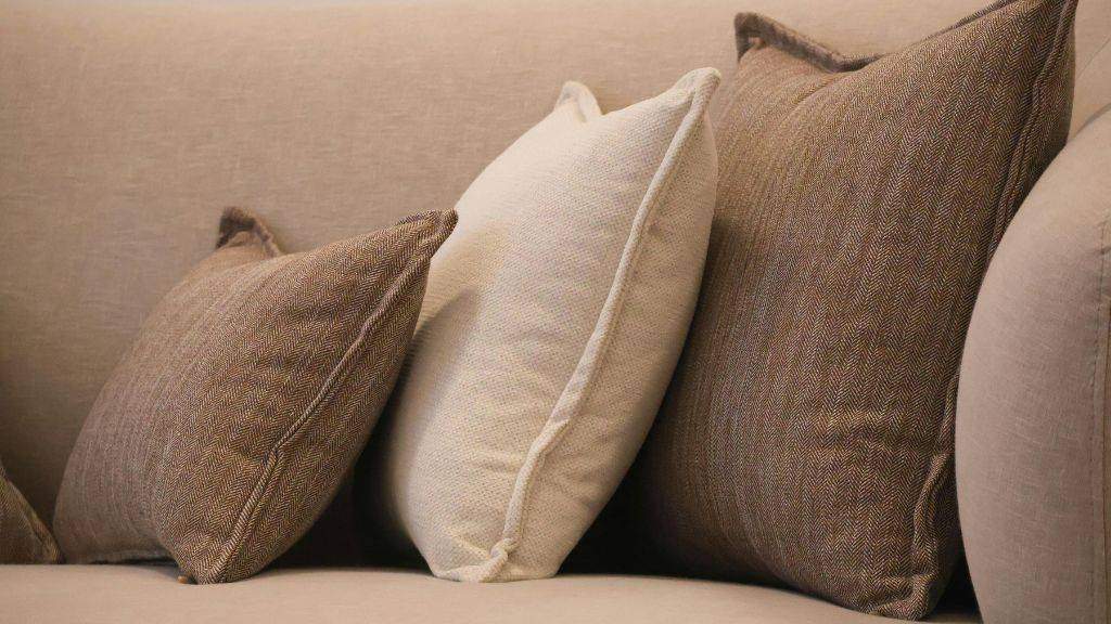 Neutral textured toss pillows layered on a luxury sofa showcasing transitional interior design for fall. 